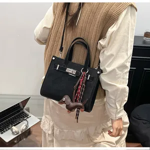 Detailed view of a black tote bag with metal twist lock and brown dachshund dog charm