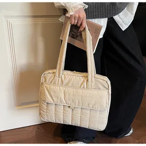 Detalle del bolso tote acolchado beige que muestra la textura suave y la solapa exterior