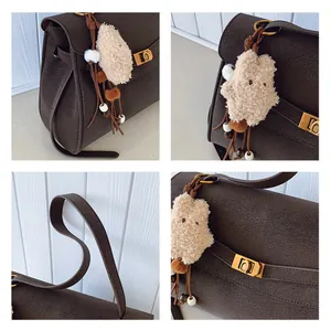 Macro detail of dark brown suede tote with gold twist lock and plush star charm accessory