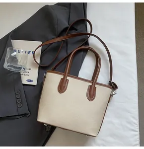 Detalle del bolso de lona con adornos de cuero marrón y correa de hombro ajustable