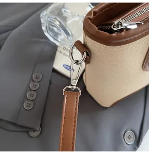 Detalle de bolso saco de lona con ribete de piel sintética marrón y gancho metálico plateado