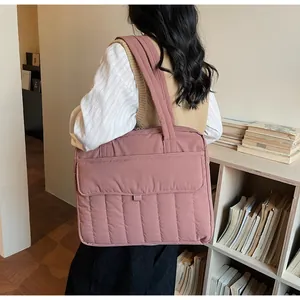 Detalle de bolsa tote acolchada rosa con asas anchas y bolsillo frontal grande