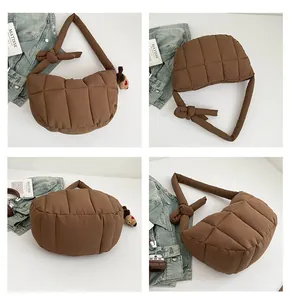 Vista dettagliata di una borsa a luna trapuntata marrone con tracolla imbottita e nodo decorativo