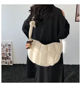 Borsa a mezzaluna trapuntata beige con ciondolo a orsetto indossata da una modella