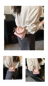 Détail du sac seau rose matelassé avec chaîne dorée et fermoir rotatif en métal sur sangle