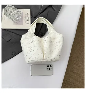Vista dettagliata della borsa in tela bianca con stampe di stelle argentate e tasche