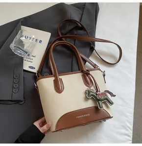 Detalle del bolso tipo cubo de lona con adornos de cuero y colgante de caballo decorativo