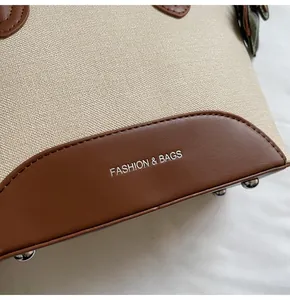 Detalle de bolso bucket de tela beige con base de cuero marrón y tachuelas de plata