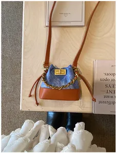Vue détaillée d'un mini sac seau en jean avec chaîne dorée sur une table en bois