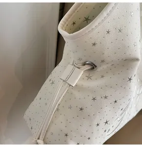 Détail du sac cabas blanc cassé avec texture côtelée et rivets en forme d'étoile