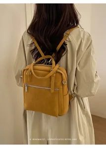 Detail eines senfgelben Rucksacks im Vintage-Look mit geprägtem Text und Metallreißverschluss