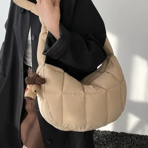 Borsa a nuvola trapuntata beige con ciondolo a orsetto, indossata a spalla per tempo libero