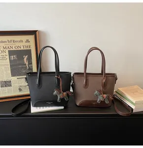 Detalle de bolsos tipo cubo minimalistas en negro y marrón con colgantes de caballo