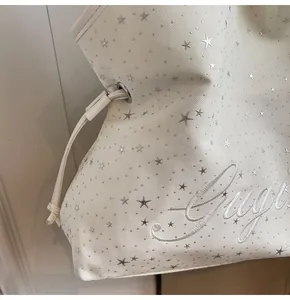 Détail du sac fourre-tout en tissu crème avec motifs d'étoiles argentées et broderie