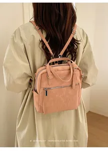 Rückansicht eines Models mit einem rosa Rucksack aus mattem Leder mit Prägebuchstaben