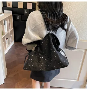 Gros plan du sac fourre-tout noir brodé d'étoiles avec un pendentif en cuir en étoile