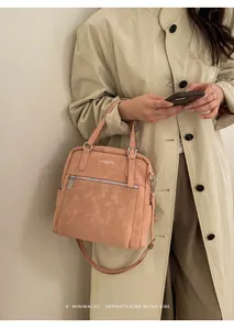 Detail der aprikosenrosa Ledertasche mit geprägtem Logo und Metallschnallen