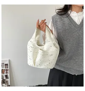 Dettaglio borsa a secchiello in tela bianca con stelle d'argento e tasche multiple