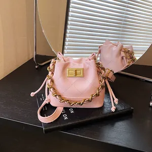 Détail d'un sac seau rose matelassé avec chaîne dorée sur un accessoire de livre