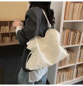 Détail du sac cabas blanc avec motifs d'étoiles grises et cordon de serrage latéral