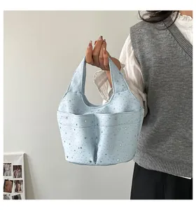 Dettaglio borsa a secchiello azzurra con stelle argentate e doppie tasche, portata dal modello