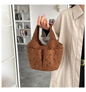 Dettaglio borsa a mano in velluto marrone con fiocchi dolci e doppie tasche frontali