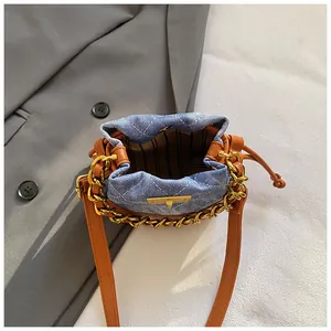Vue de dessus du mini sac seau en denim bleu avec détails en cuir beige et doublure rayée