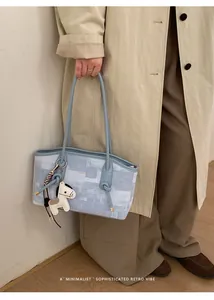 Gros plan d'un sac cabas bleu à texture abstraite avec breloque en forme de cheval