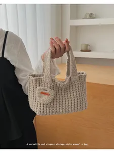 Primer plano del bolso beige tejido a mano con textura de panal y etiqueta de cuero