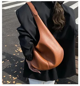 Brown lychee leather hobo bag worn by model in an autumn outdoor setting