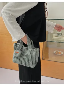 Detalle del bolso gris hecho a mano con colgante de corazón y etiqueta Hand Made