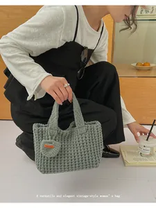 Detalle de bolso de crochet verde con colgante de corazón y textura de punto grueso