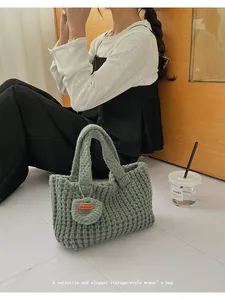 Detalle de bolso de ganchillo verde grisáceo con punto calado y etiqueta de cuero artesanal