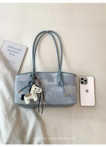 Détail du sac cabas en denim bleu avec sangle à nœuds, breloque poney et grand volume
