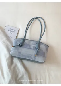 Détail du tissu à carreaux bleu clair et des nœuds en cuir sur le sac à bandoulière