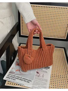 Detalle de bolso de punto artesanal marrón caramelo con un colgante circular único
