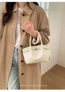 Close-up of cream pebble leather bucket bag with metallic twist lock and double handles