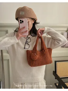 Detalle del bolso de ganchillo hecho a mano color caramelo con colgante de corazón y marca