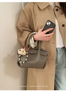 Close-up of pebble leather bucket bag with cute bear charm and branded texture detail