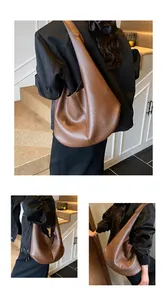 Detail of a brown lychee pattern leather crescent tote bag with a wide shoulder strap