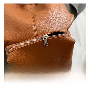 Close-up of pebble grain leather texture and premium silver hardware on brown tote bag