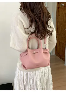 Pink lychee texture bucket bag shown on a model with white sweater and pleated skirt
