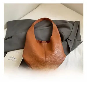 Detail view of brown pebbled leather texture on a minimalist hobo shoulder bag