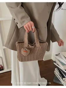 Detalle de bolso de punto marrón con texturas cuadradas y colgante de corazón artesanal