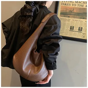 Brown leather hobo bag shoulder view showing large capacity and soft slouchy texture