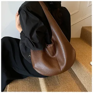 Detailed view of the dark brown lychee leather texture and vertical stitching on hobo tote