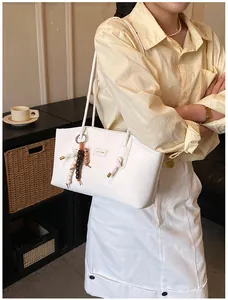 Close-up of white leather tote bag with long straps and bead fringe charm detail