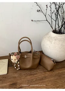 Flat lay of caramel leather bucket bag set with mini pouch and cute teddy bear charm