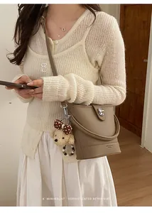 Detail of beige lychee leather bucket bag with silver twist lock and teddy bear charm
