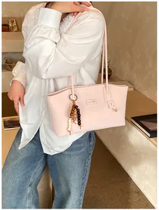 Detailed shot of pink tote bag with beaded charm and stylish knotted shoulder strap detail